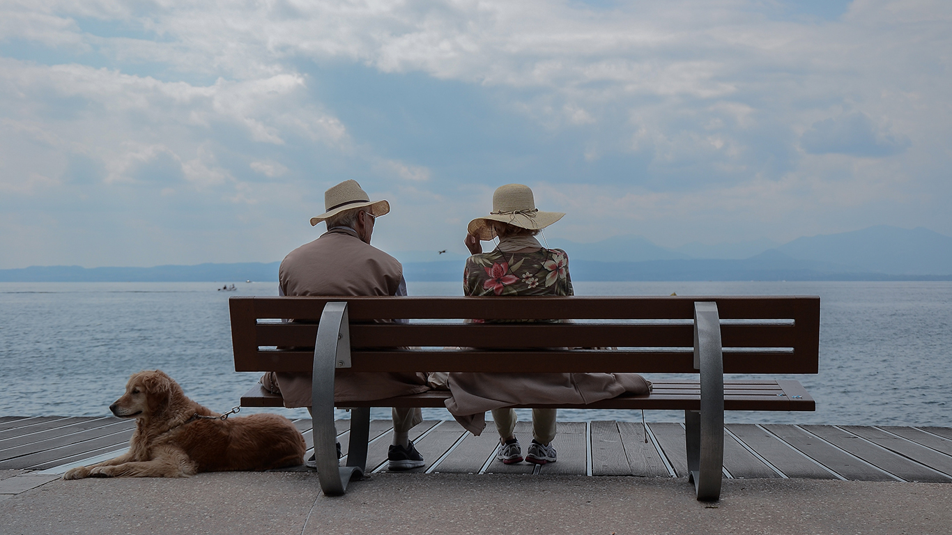 older couple sitting on bench with dog