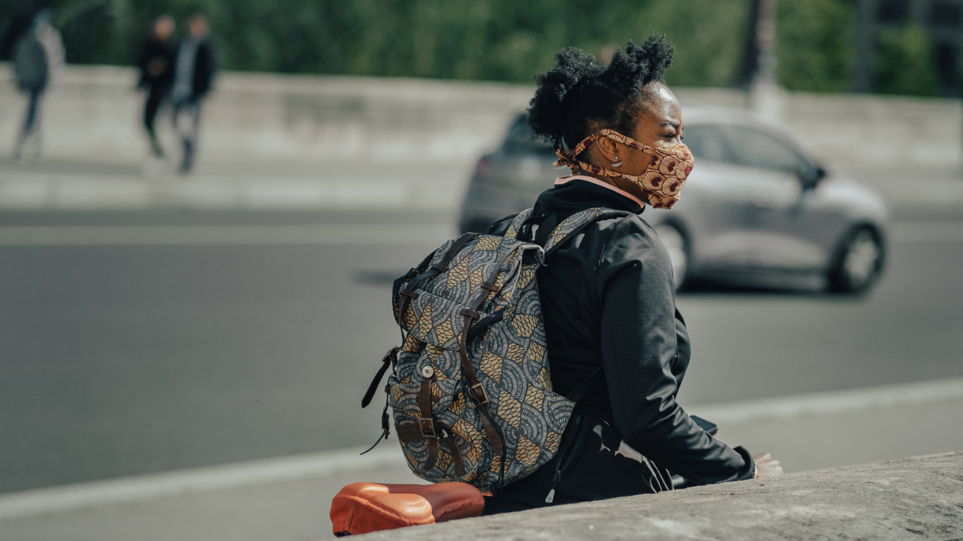 woman crossing a street with a mask on